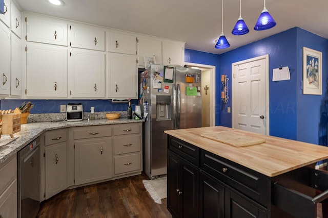 kitchen with hanging light fixtures, light stone countertops, appliances with stainless steel finishes, and white cabinets