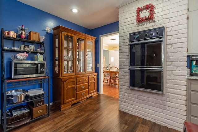 kitchen featuring black double oven and dark wood-type flooring