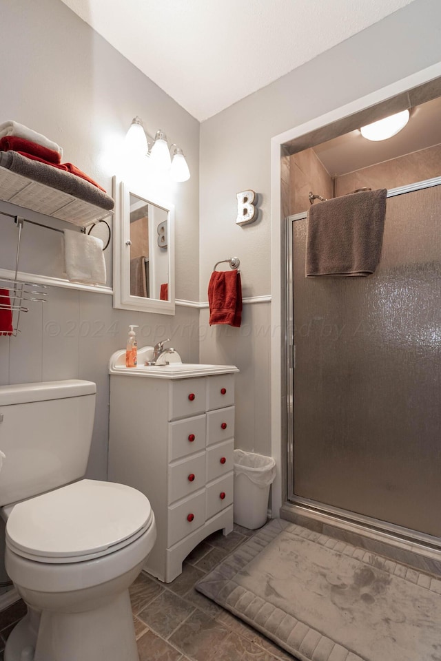 bathroom featuring vanity, toilet, and a shower with shower door