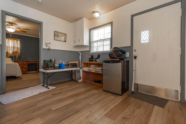 kitchen featuring ceiling fan, light wood-type flooring, white cabinets, and stainless steel refrigerator