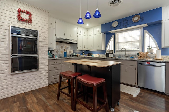 kitchen with hanging light fixtures, dark hardwood / wood-style floors, black appliances, white cabinets, and a kitchen island