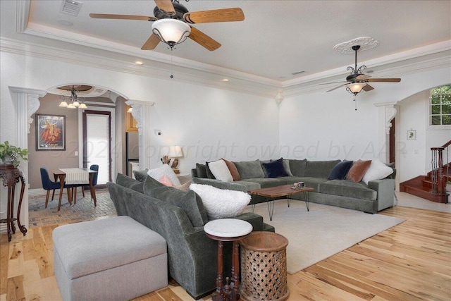 living room with plenty of natural light, light hardwood / wood-style flooring, a tray ceiling, and decorative columns