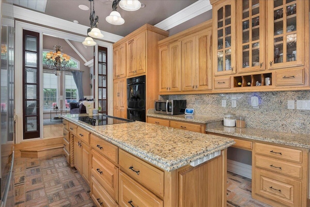 kitchen with light stone countertops, ornamental molding, black appliances, a kitchen island, and hanging light fixtures