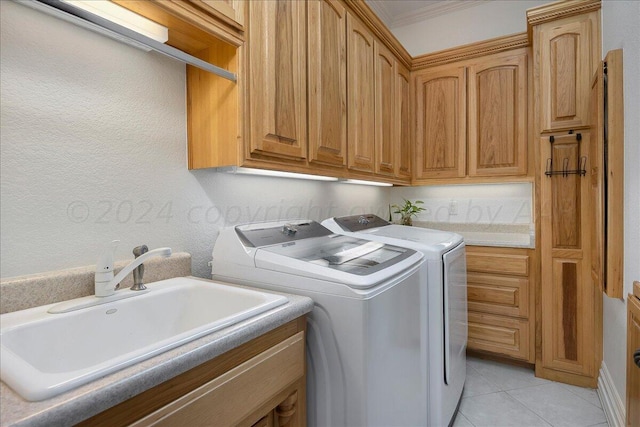 laundry room with cabinets, washer and clothes dryer, crown molding, sink, and light tile patterned floors