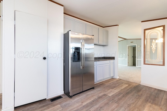 kitchen with stainless steel fridge, light hardwood / wood-style floors, and white cabinetry