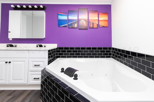 bathroom with tiled bath, vanity, and hardwood / wood-style flooring