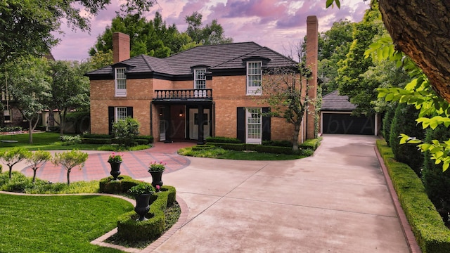 2802 S Hughes St, Amarillo, TX 79109 - french country inspired facade featuring a chimney, brick siding, a garage, concrete driveway, and a balcony