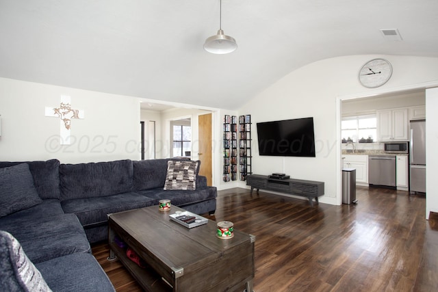 living area featuring plenty of natural light, dark wood-style floors, visible vents, and vaulted ceiling