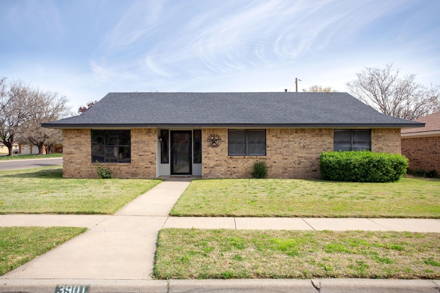 ranch-style house with a front yard, a shingled roof, and brick siding