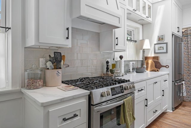 2215 S Hughes St, Amarillo, TX 79109 - kitchen with appliances with stainless steel finishes, white cabinets, backsplash, and ventilation hood