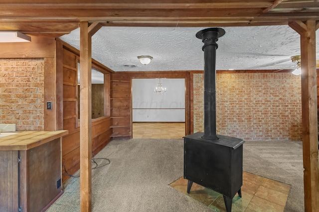 unfurnished living room with brick wall, wood walls, a chandelier, a textured ceiling, and light colored carpet