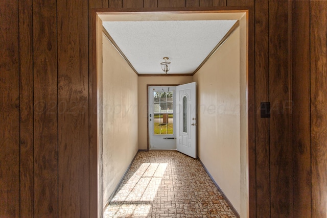 doorway to outside featuring ornamental molding and a textured ceiling