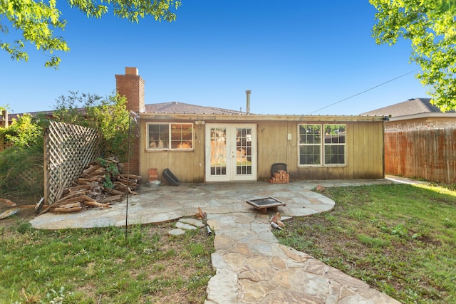 rear view of house with french doors, a patio, and a lawn