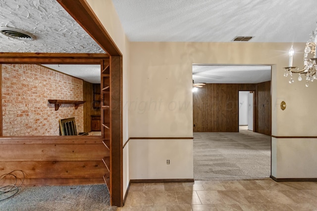 carpeted spare room with a textured ceiling, ceiling fan with notable chandelier, and wooden walls