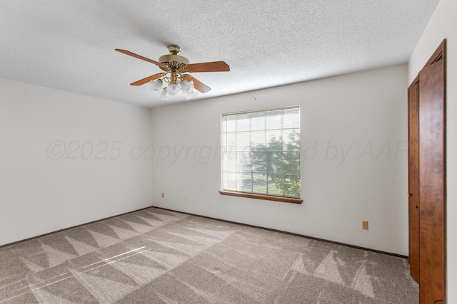 carpeted spare room featuring ceiling fan and a textured ceiling