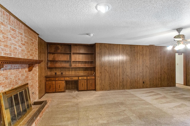 unfurnished living room featuring wood walls, a fireplace, light colored carpet, and built in desk