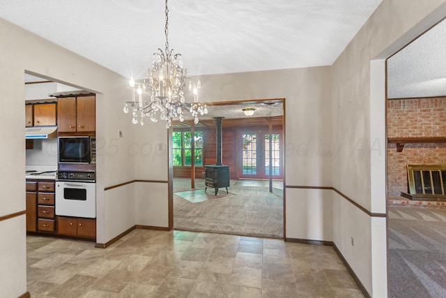 kitchen featuring white oven, black microwave, decorative light fixtures, a notable chandelier, and a wood stove