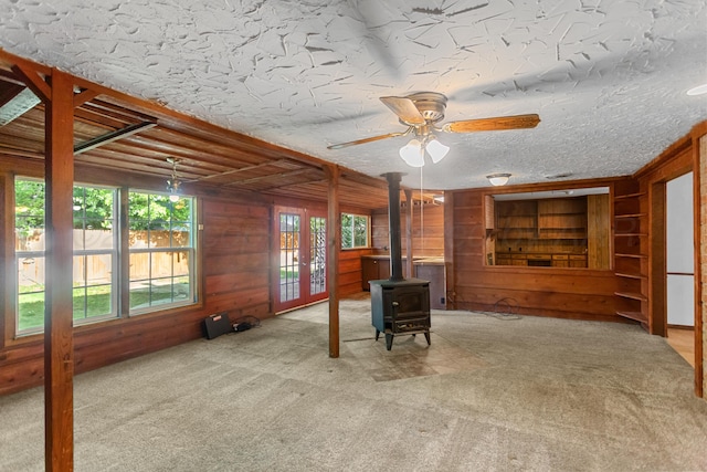 interior space featuring ceiling fan, wood walls, and a wood stove