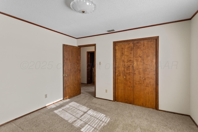 unfurnished bedroom featuring a textured ceiling, light colored carpet, and a closet