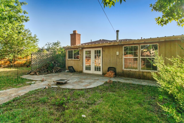 rear view of house featuring french doors, a patio, and a lawn