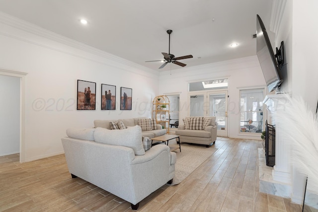 living area featuring ornamental molding, a fireplace with raised hearth, light wood finished floors, and a ceiling fan