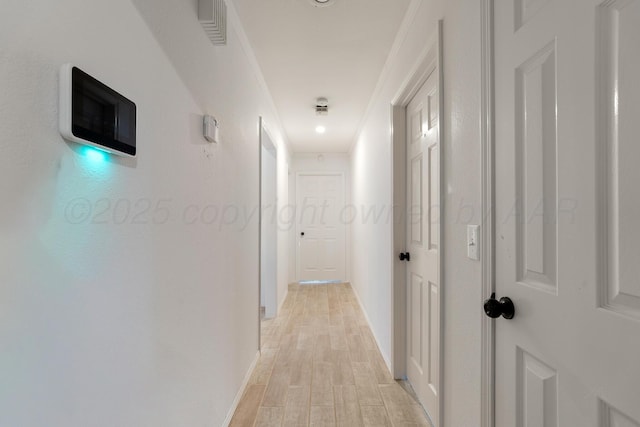 hallway featuring baseboards, visible vents, and light wood finished floors