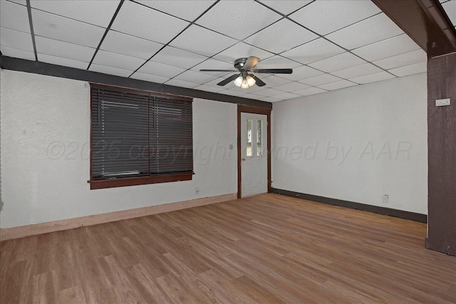 spare room with a paneled ceiling, a ceiling fan, baseboards, and wood finished floors