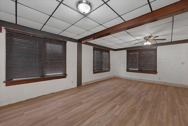 empty room with a paneled ceiling, ceiling fan, and wood finished floors