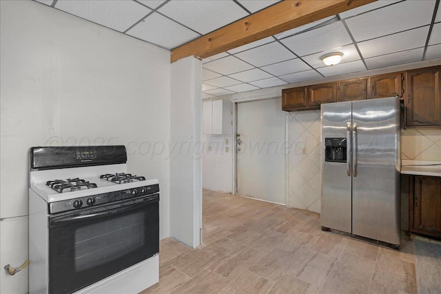 kitchen with light countertops, gas stove, stainless steel fridge, and a paneled ceiling