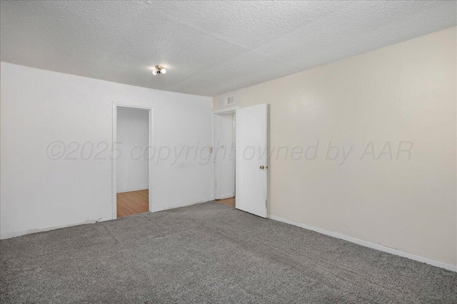 unfurnished bedroom with a textured ceiling, visible vents, and carpet flooring