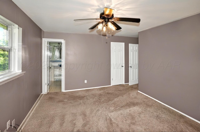 carpeted empty room with baseboards and a ceiling fan