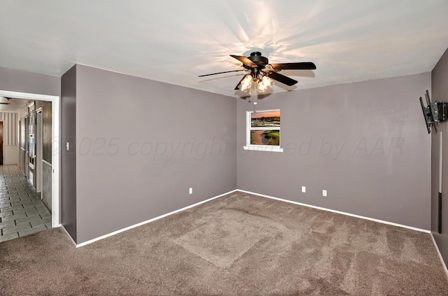 carpeted empty room featuring a ceiling fan and baseboards