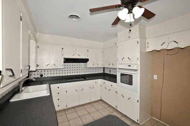 kitchen featuring oven, a sink, black electric cooktop, dark countertops, and ventilation hood