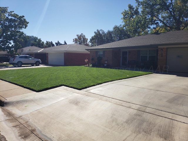ranch-style house featuring an attached garage, concrete driveway, and a front yard