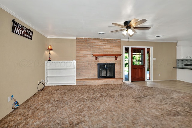 unfurnished living room with ceiling fan, carpet flooring, a fireplace, ornamental molding, and tile patterned flooring