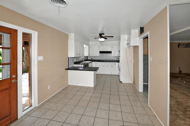 kitchen with dark countertops, a peninsula, healthy amount of natural light, backsplash, and crown molding