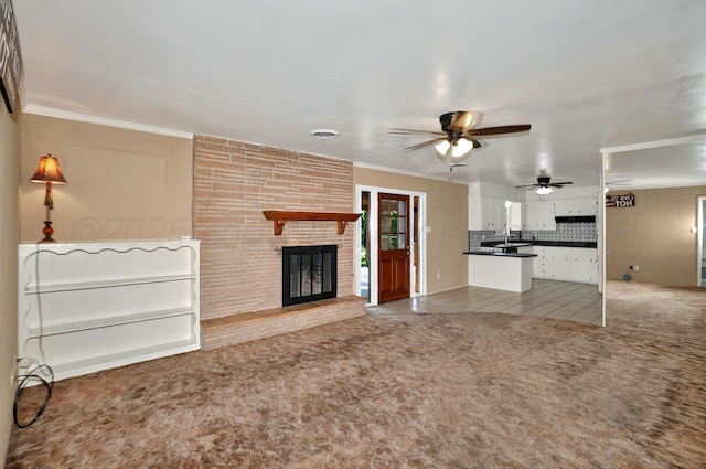 unfurnished living room featuring light carpet, ceiling fan, a fireplace, and ornamental molding