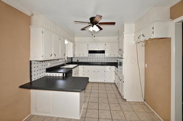 kitchen with dark countertops, a sink, a ceiling fan, tasteful backsplash, and a peninsula