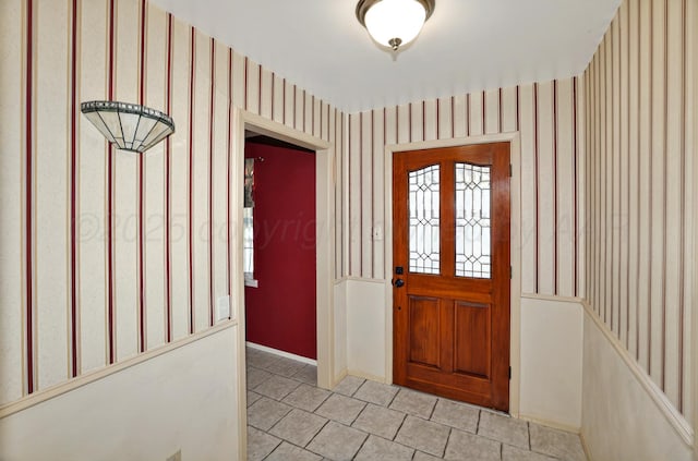 foyer with wallpapered walls, light tile patterned floors, and baseboards