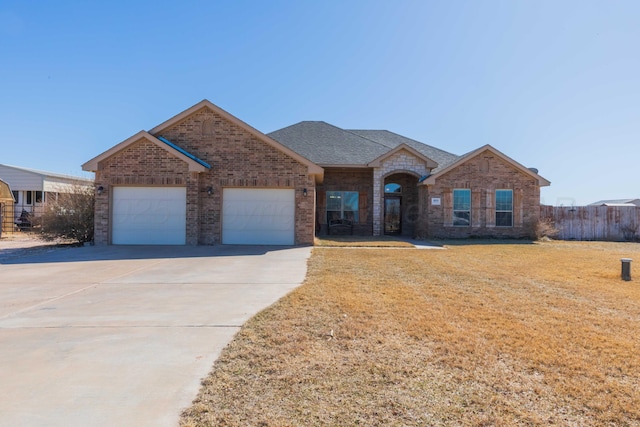 single story home with a garage, brick siding, concrete driveway, roof with shingles, and a front yard