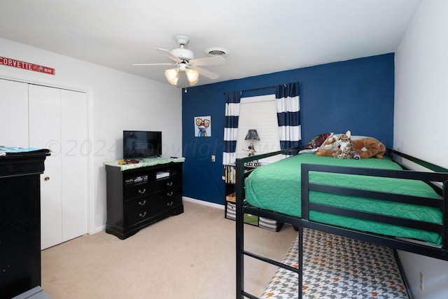 bedroom with ceiling fan, light colored carpet, and a closet