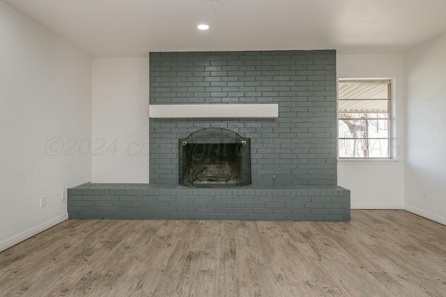 unfurnished living room with hardwood / wood-style flooring and a brick fireplace