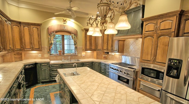 kitchen featuring tile counters, decorative backsplash, sink, an island with sink, and appliances with stainless steel finishes