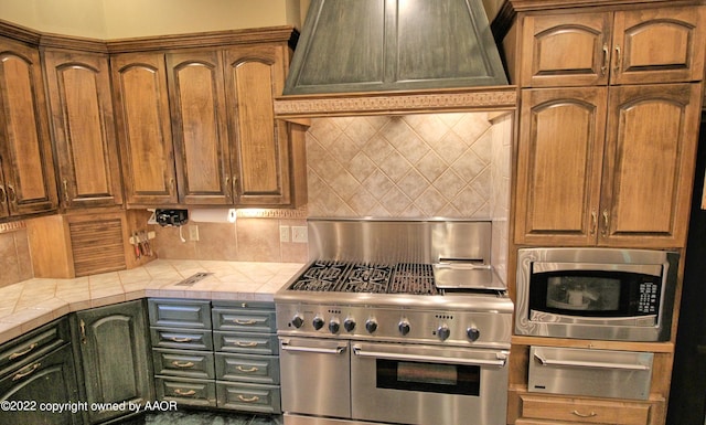 kitchen featuring tile counters, appliances with stainless steel finishes, custom exhaust hood, and backsplash