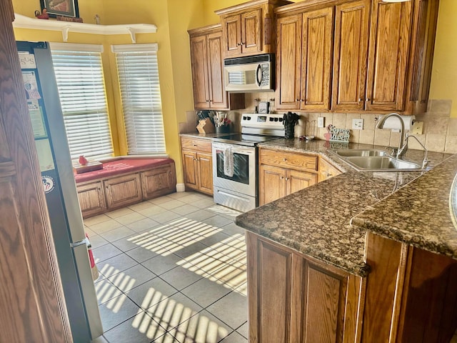 8422 Addison Dr, Amarillo, TX 79119 - kitchen with stainless steel appliances, light tile patterned floors, and brown cabinetry