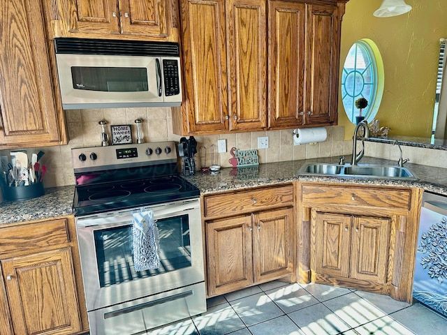 8422 Addison Dr, Amarillo, TX 79119 - kitchen featuring appliances with stainless steel finishes, brown cabinets, tasteful backsplash, and light tile patterned flooring