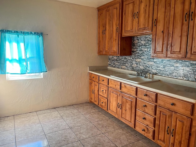 kitchen with light tile patterned floors, decorative backsplash, and sink