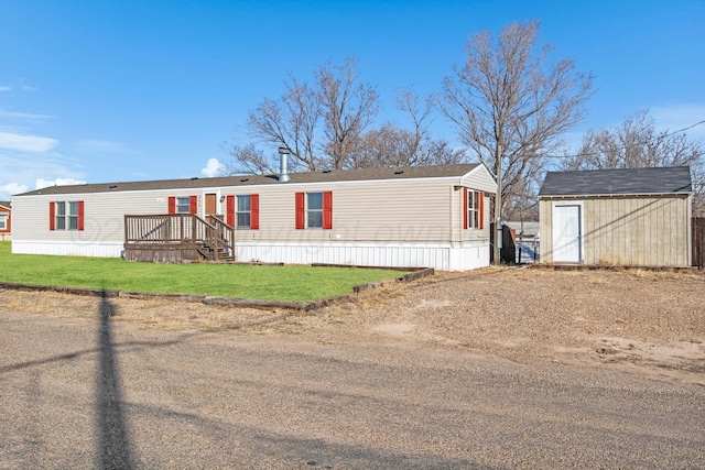 manufactured / mobile home featuring a front yard and a storage shed