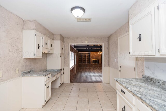 2709 Mohawk Dr, Amarillo, TX 79109 - kitchen with light tile patterned floors, white cabinetry, wainscoting, and wallpapered walls