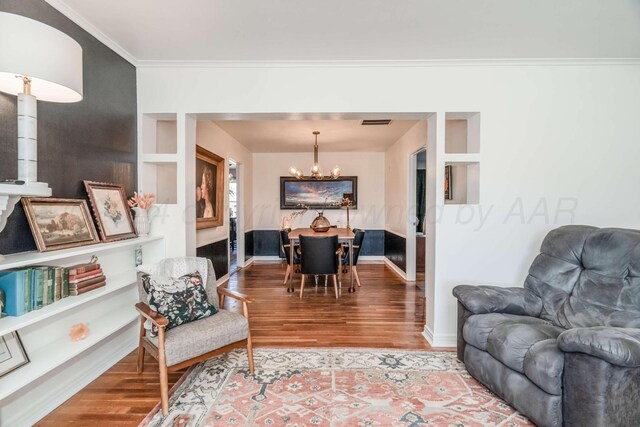 living room featuring hardwood / wood-style flooring, an inviting chandelier, and crown molding